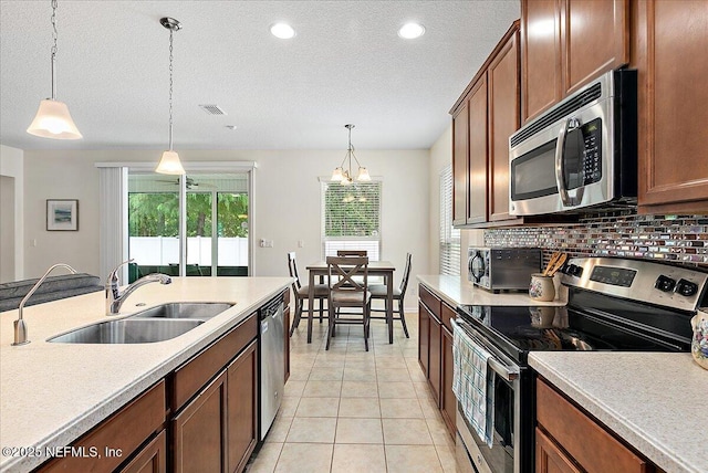 kitchen featuring appliances with stainless steel finishes, hanging light fixtures, a notable chandelier, and sink