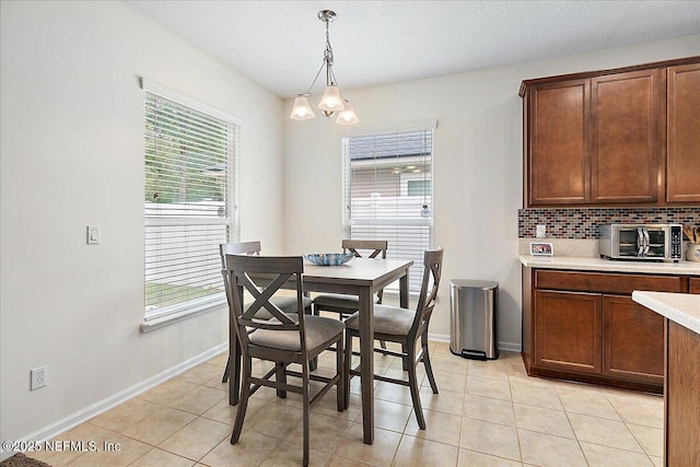 dining area with a notable chandelier, a textured ceiling, and light tile patterned floors