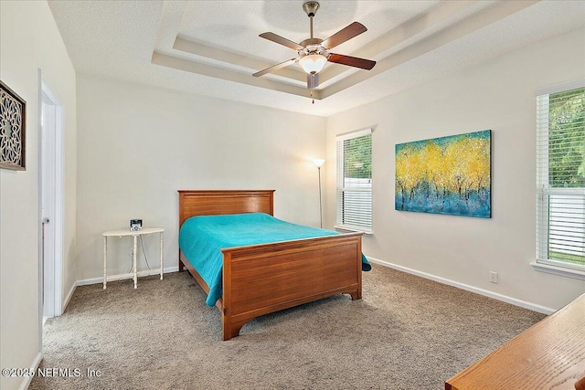 carpeted bedroom featuring ceiling fan, a raised ceiling, and a textured ceiling