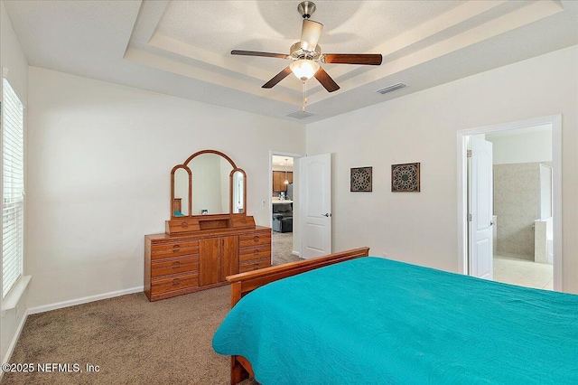 bedroom with connected bathroom, carpet, ceiling fan, and a tray ceiling