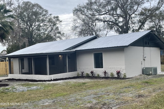 back of property featuring cooling unit, a sunroom, and a lawn