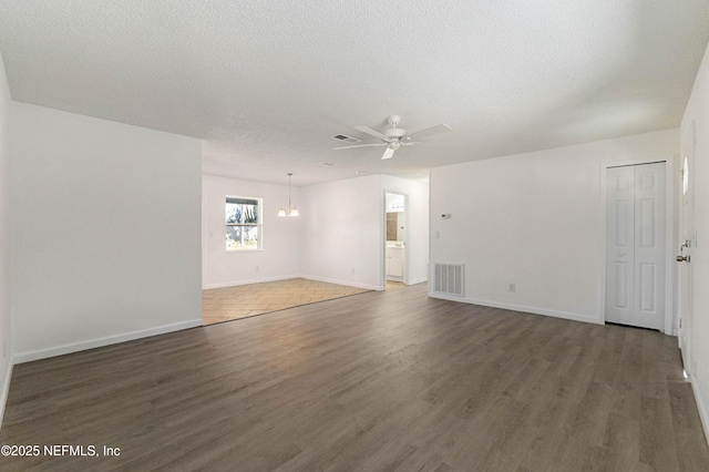 spare room with dark hardwood / wood-style flooring, ceiling fan with notable chandelier, and a textured ceiling