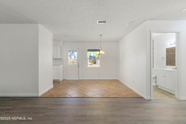 interior space with sink, light hardwood / wood-style floors, a textured ceiling, and a notable chandelier