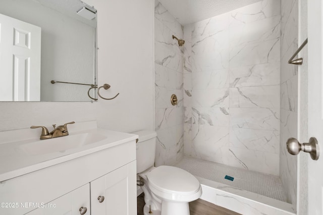 bathroom featuring vanity, tiled shower, and toilet