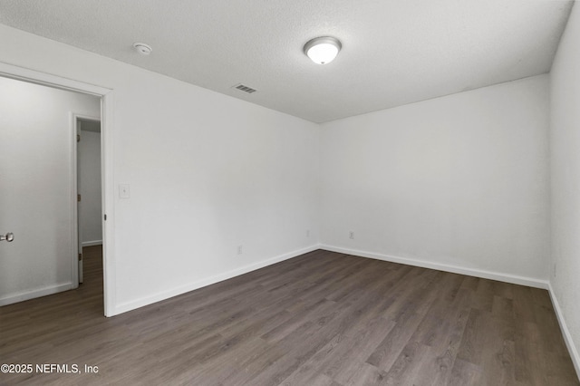 spare room featuring dark hardwood / wood-style floors and a textured ceiling