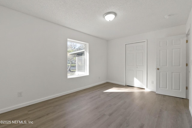 unfurnished bedroom with wood-type flooring, a closet, and a textured ceiling