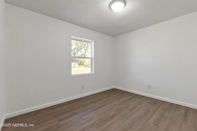 spare room with dark hardwood / wood-style floors and a textured ceiling