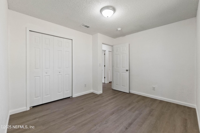 unfurnished bedroom featuring hardwood / wood-style floors, a closet, and a textured ceiling