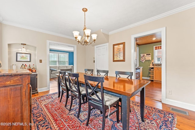 dining room featuring crown molding, hardwood / wood-style floors, and an inviting chandelier