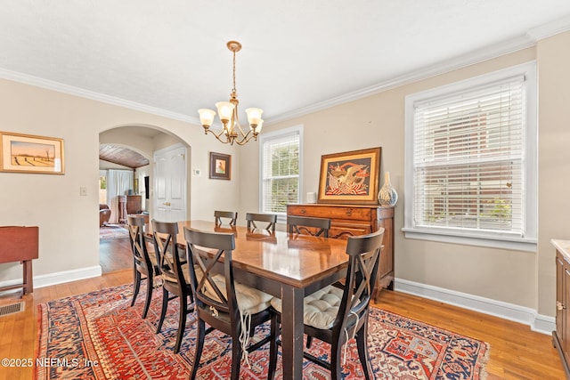 dining space featuring crown molding, a chandelier, and light wood-type flooring