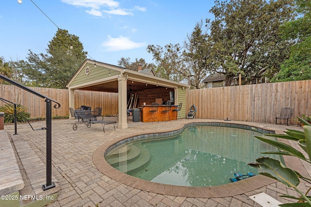 view of swimming pool featuring a patio and an outdoor bar