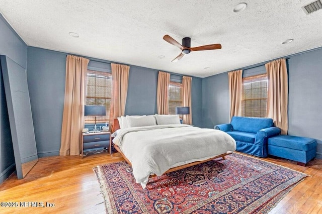 bedroom with hardwood / wood-style floors, a textured ceiling, and ceiling fan