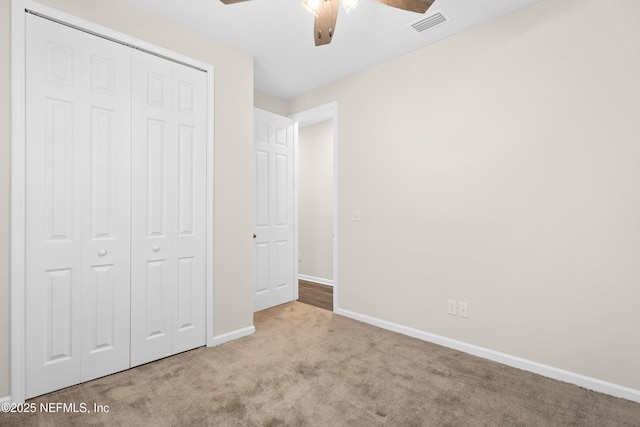 unfurnished bedroom featuring ceiling fan, a closet, and light carpet