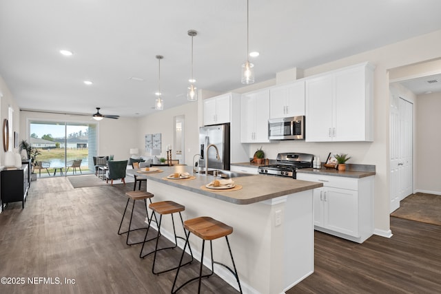 kitchen with ceiling fan, pendant lighting, a center island with sink, sink, and stainless steel appliances