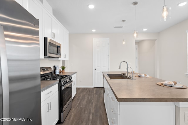 kitchen with stainless steel appliances, sink, white cabinets, and an island with sink