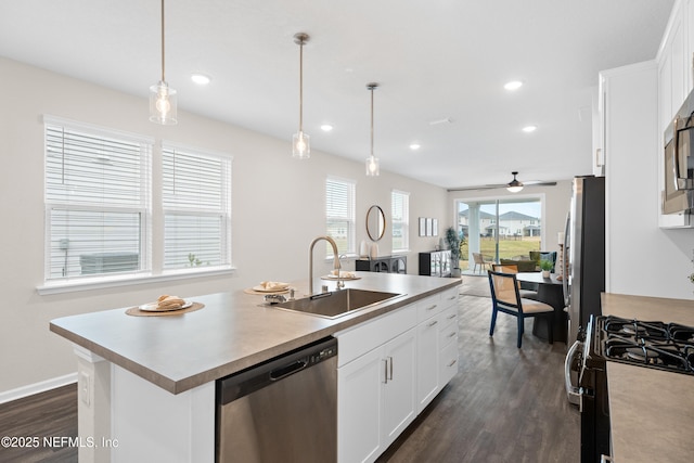 kitchen featuring sink, white cabinets, stainless steel appliances, and an island with sink