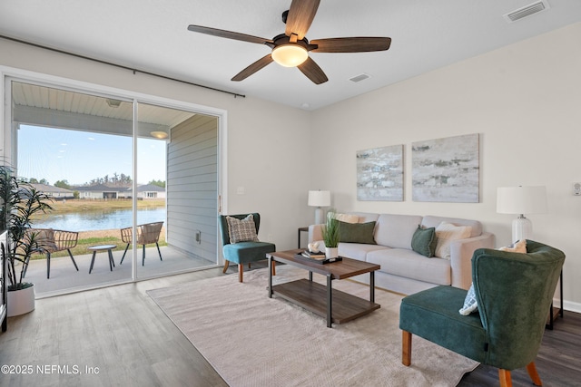 living room featuring ceiling fan, a water view, and wood-type flooring