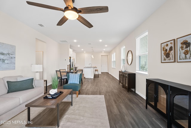 living room with dark wood-type flooring, sink, and ceiling fan