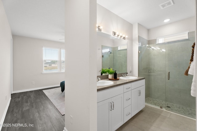 bathroom with hardwood / wood-style floors, walk in shower, and vanity