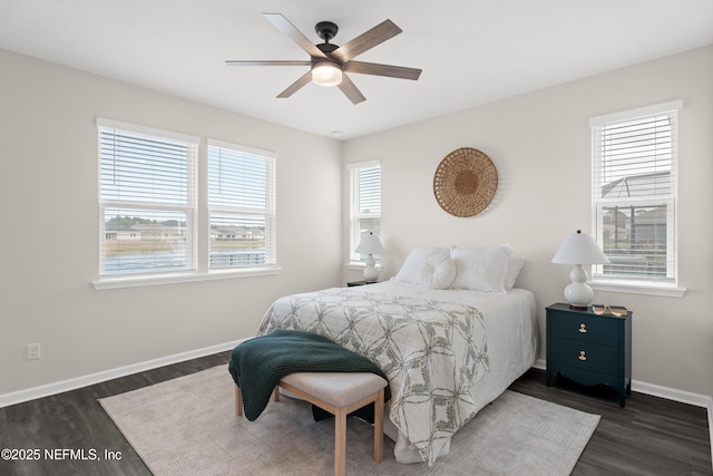 bedroom featuring ceiling fan, dark hardwood / wood-style floors, and multiple windows