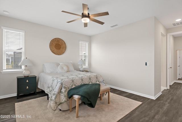 bedroom featuring ceiling fan, dark hardwood / wood-style flooring, and multiple windows