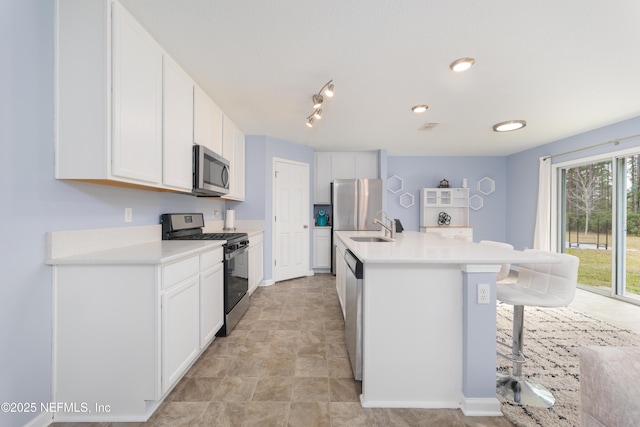 kitchen with stainless steel appliances, a kitchen island with sink, a breakfast bar, and white cabinetry