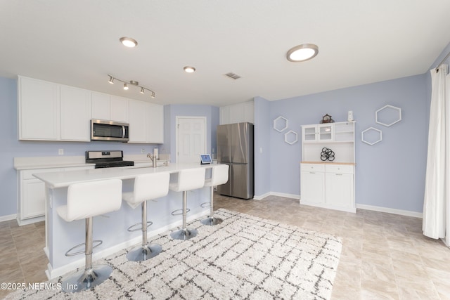 kitchen with stainless steel appliances, a center island with sink, white cabinets, and a breakfast bar