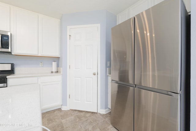 kitchen with white cabinets, stainless steel appliances, and light stone counters