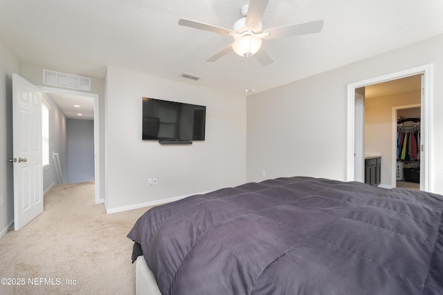 bedroom featuring a closet, a walk in closet, ceiling fan, and light carpet