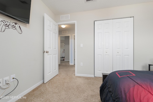 bedroom featuring light colored carpet, a closet, and a textured ceiling