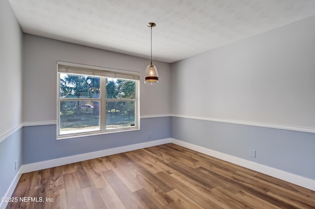 unfurnished room with a textured ceiling and hardwood / wood-style floors