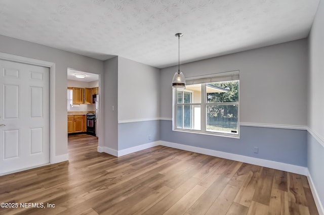 unfurnished dining area with a textured ceiling and hardwood / wood-style flooring