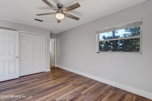 unfurnished bedroom with ceiling fan, a closet, and dark hardwood / wood-style floors