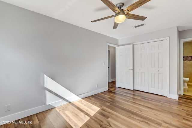 unfurnished bedroom featuring ensuite bathroom, ceiling fan, light wood-type flooring, and a closet