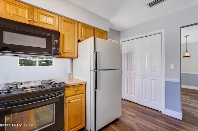 kitchen featuring dark wood-type flooring, decorative light fixtures, and black appliances