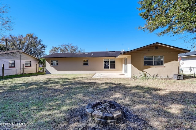 rear view of property featuring central AC, an outdoor fire pit, a yard, and a patio