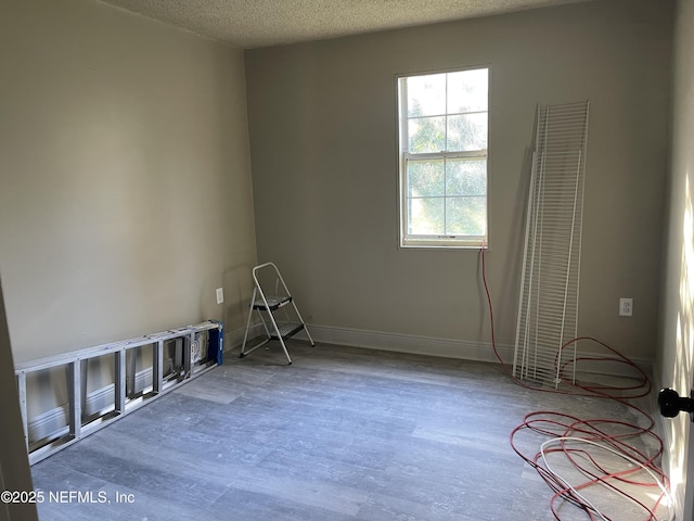 unfurnished room with a textured ceiling and hardwood / wood-style floors