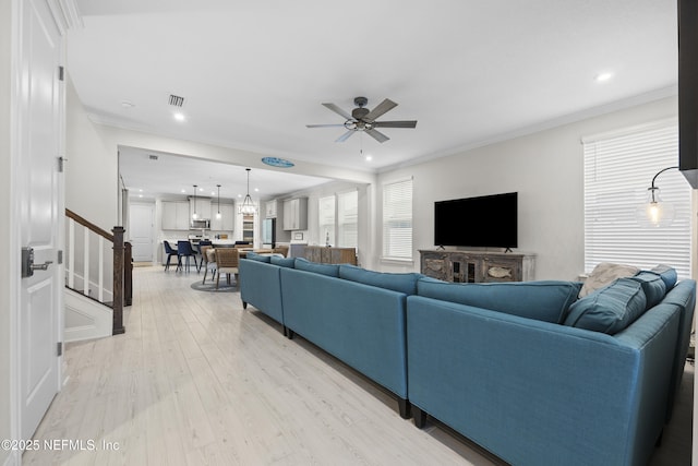 living room with light hardwood / wood-style floors, ceiling fan, and ornamental molding