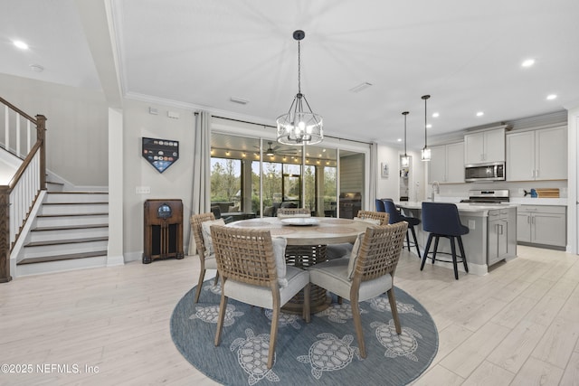 dining area featuring sink, ornamental molding, and light wood-type flooring