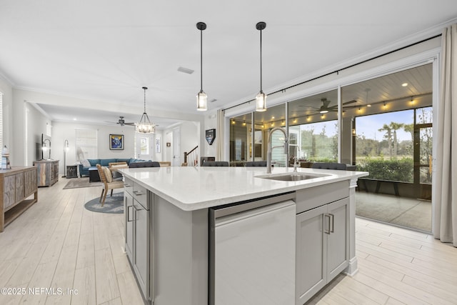 kitchen with dishwasher, gray cabinetry, sink, decorative light fixtures, and an island with sink