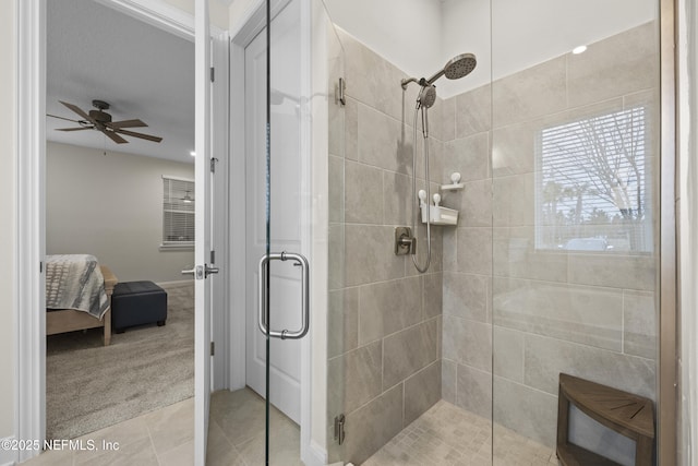 bathroom featuring a shower with shower door, ceiling fan, and tile patterned floors