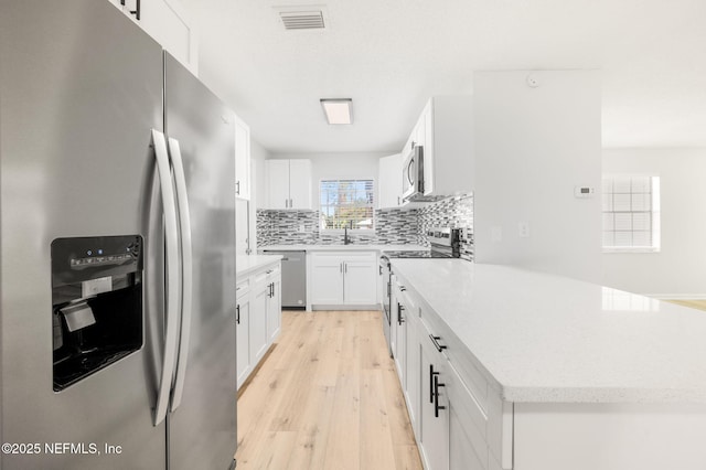 kitchen with white cabinets, appliances with stainless steel finishes, tasteful backsplash, and a kitchen island