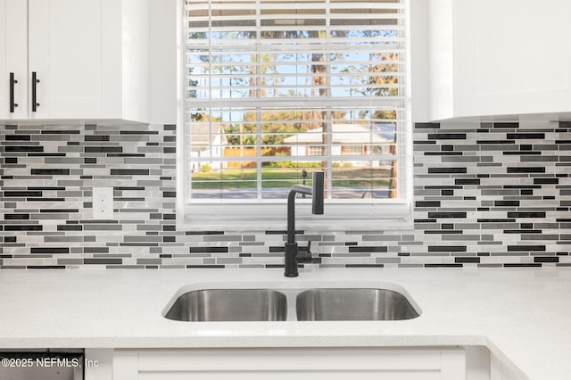 kitchen with tasteful backsplash, white cabinets, plenty of natural light, and sink