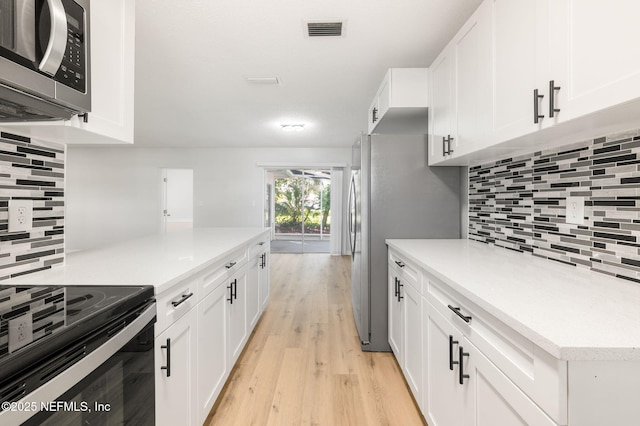 kitchen featuring light hardwood / wood-style floors, decorative backsplash, stainless steel appliances, and white cabinetry