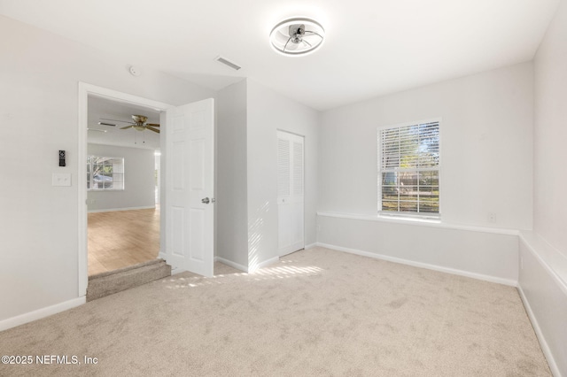 carpeted empty room featuring ceiling fan and a wealth of natural light