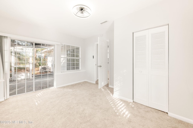 unfurnished bedroom featuring light colored carpet, access to exterior, and a closet