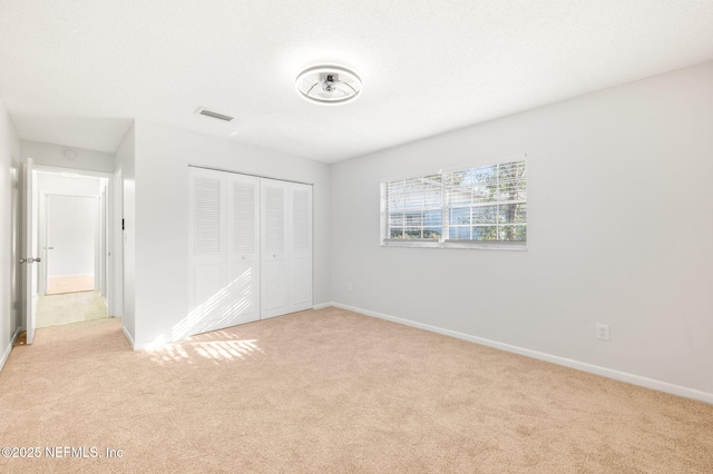 unfurnished bedroom with light carpet and a closet