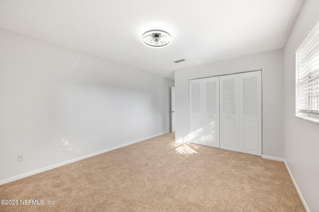 unfurnished bedroom with light carpet and a closet