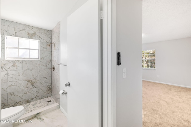 bathroom with toilet and a tile shower