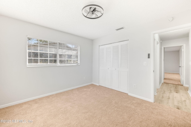 unfurnished bedroom with light colored carpet and a closet